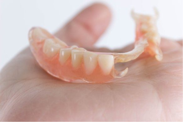 Hand holding partial dentures